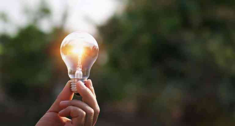 hand holding light bulb in nature background. concept solar ener